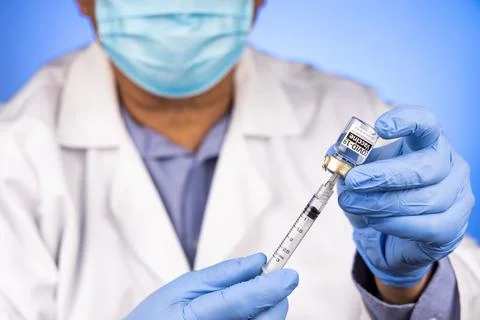 Close-up and focus on syringe inserted into Covid-19 vaccine vial by Asian Stock Photos