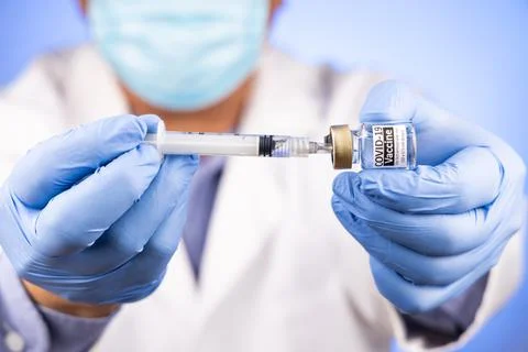 Close-up and focus on syringe inserted into Covid-19 vaccine vial by Asian Foto stock