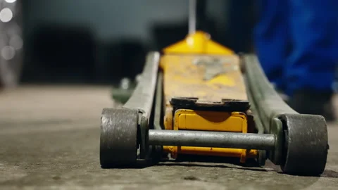 Close-up and operational view of a yellow hydraulic floor jack used by a Stock-Footage 333839317