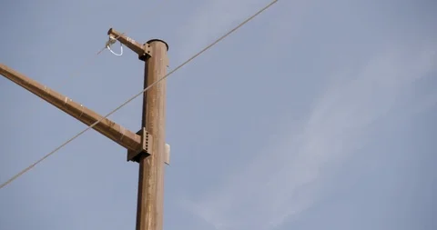 Close Up and Pan Across Single Rusted Pole with Power Lines Against Blue Sky Stock Footage 89942590