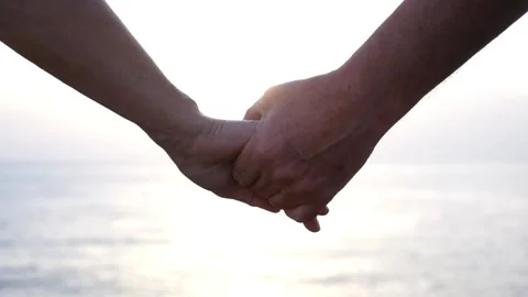 Close up and portrait of hands taking care with each other with sunset and sea o Stock Footage 135683344