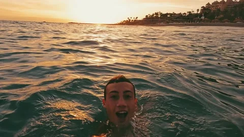 Close up and portrait of young man holding a camera and swimming underwater in t Stock Footage 204799533
