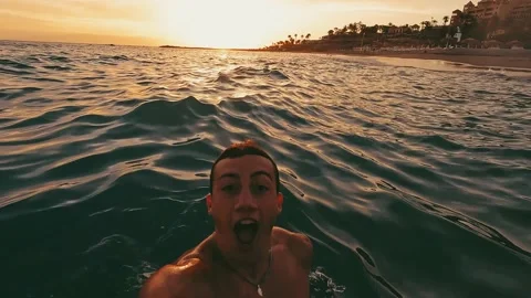 Close up and portrait of young man holding a camera and swimming underwater in t 库存影片 204799748