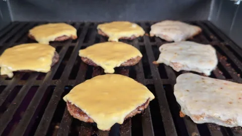 Close-up and selective focus cheeseburgers and chicken burgers on hot grill. Stockbeeldmateriaal 337575346