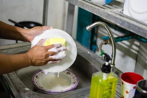 Close up and selective focus on the hands of a woman washing dishes and Rem.. Stock Photos