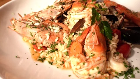 Close-up and slow-motion of risotto with jumbo shrimp rotation on a white pla Stock Footage 129928022