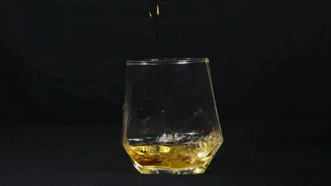 Close-up and slow-motion video of whiskey pouring inside the glass with a black  Stock-Footage 321696822