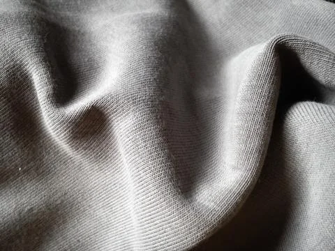 Close-up and texture of a gray knitted fabric, slightly folded in waves or wr Foto stock
