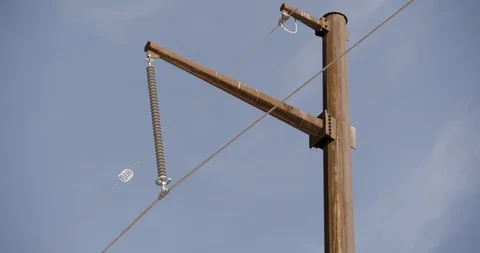 Close Up and Tilt Down on Single Rusted Pole with Power Lines Against Blue Sky Stock Footage 89942582