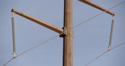 Close Up and Tilt Up on Single Rusted Pole with Power Lines Against Blue Sky Stock Footage 89942586