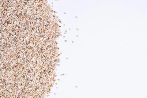 A close up and top down view on grains of sand from the beach against a white 스톡 사진