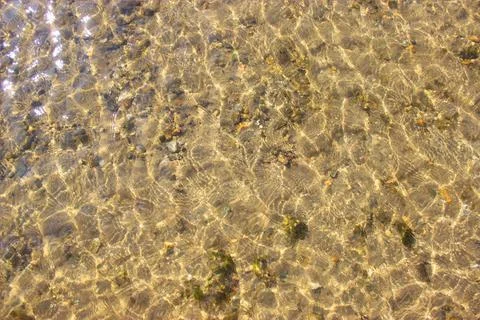 Close-up and top view of shiny transparent yellow sand and stones on the beach Stock Photos