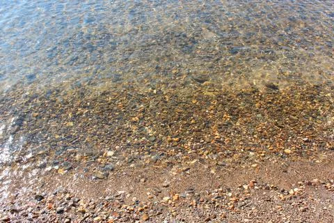 Close-up and top view of shiny transparent yellow sand and stones on the beach Stock Photos