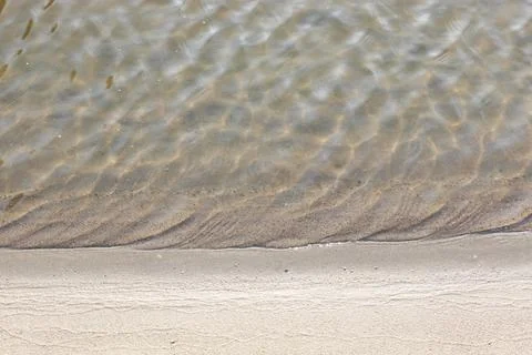 Close-up and top view of shiny transparent yellow sand and stones on the beach Stock Photos
