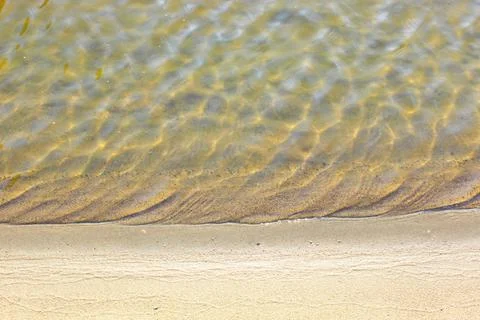 Close-up and top view of shiny transparent yellow sand and stones on the beach Stock Photos