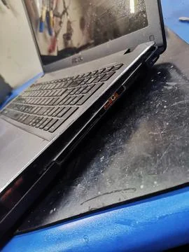 A close-up angle of a black laptop computer resting on a desk, showing severe 写真素材