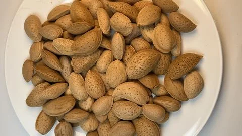 Close Up Angle View of Almonds with Shell on White Plate Stock Photos