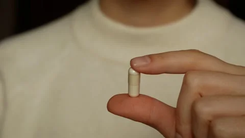 Close angle, a woman's hand gently holds a pill. Stock Footage 305925965