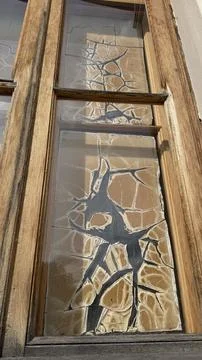Close-up angled view of cracked glass panes in a vintage wooden window frame of Stock Photos