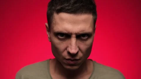 Close-up of an angry man staring intensely at the camera against a red Stock Footage 295928387