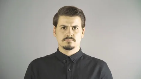 Close-up of angry young man screaming to camera. Grey dark background. Vídeos de archivo 76203382