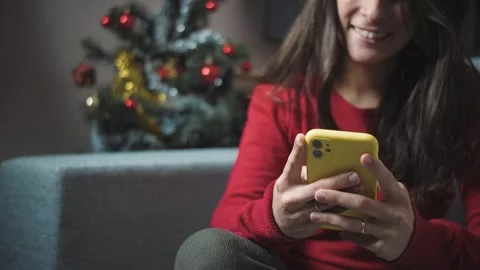 Close-up of anonymous young woman’s hands using a smartphone at home during Chri Stock Footage 346004582