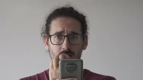 Close up of anxious man with smartphone biting his nails and looking at camera Stock Footage 161552156