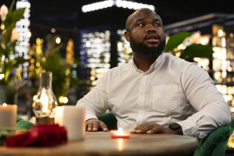 Close up of anxious man waiting alone at rooftop restaurant for date to show up Stock Photos