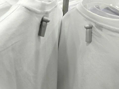 Close-up of apparel security sensors attached to blank white shirts in a departm Stock Photos