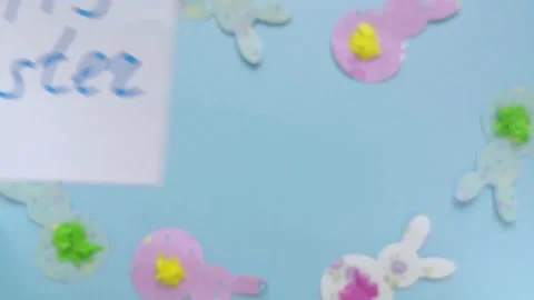 Close-up appear note with words Happy Easter on blue background with rabbits Stock Footage 147357890