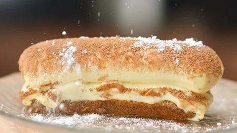 Close up appetizing eclair sprinkling sugar powder slow motion. Shot on RED 動画素材 124305257