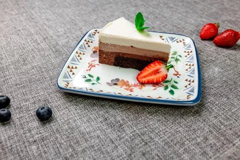 Close-up of appetizing three chocolate mousse cake with berries and mint. Stock Photos