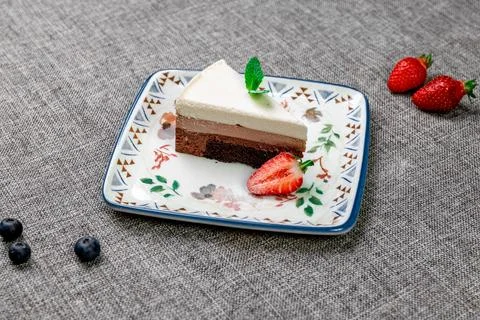 Close-up of appetizing three chocolate mousse cake with berries and mint. Stock Photos