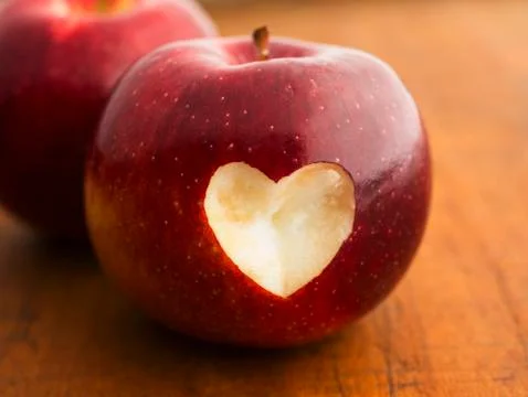 Close up of apple with missing bite in heart shape, studio shot Stock Photos