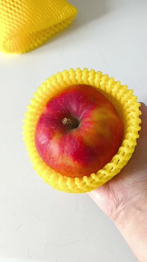 Close-up of an apple in a yellow foam net in your hand Stockbeeldmateriaal 332409994