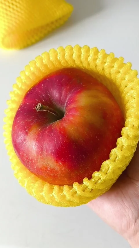 Close-up of an apple in a yellow foam net in your hand Stock-Footage 332409996