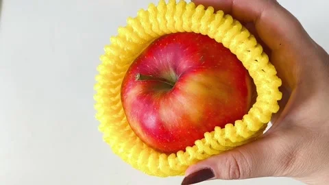 Close-up of an apple in a yellow foam net in your hand Vídeos de archivo 332410019