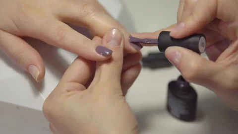 Close-up of applying gel-varnish on the nails of a young woman in a beauty salon Stock Footage 87391229
