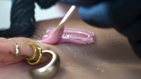 Close up of applying a pink wax to face above her hear with wooden stick 库存影片 312553430