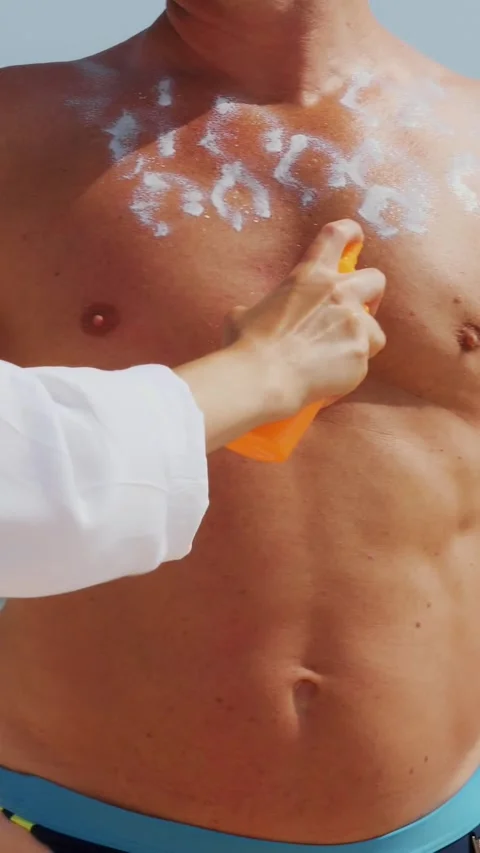 Close-up, applying sunscreen or spray lotion to man skin . on beach, under hot Stock Footage 310180871