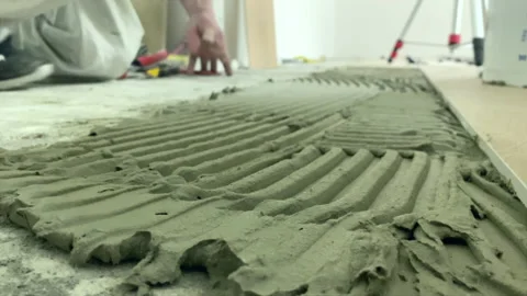 Close up. Applyng cement adhesive on ceramic tile - Installing ceramic floor Stock Footage 153682948