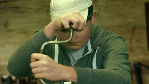 Close-up of an apprentice drilling a piece of wood with a hand drill Stock Footage 84603224