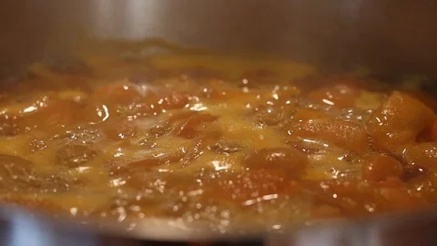 Close up of apricot jam simmering in a pot on the stove in slow motion Stock Footage 124456820