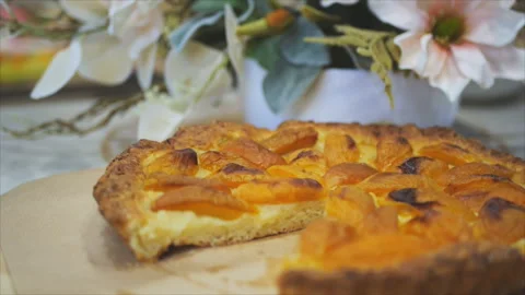 Close up of an apricot pie on a table with beautiful flowers Видео 155000063