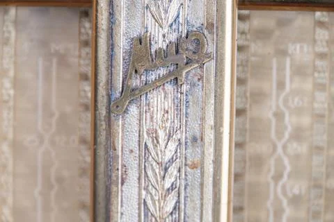 Close-up of an Arabic script emblemlogo on a textured wall, surrounded by int Stock Photos