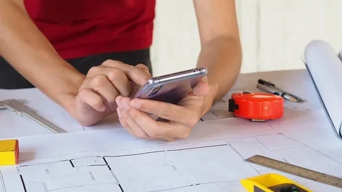 Close up of Architect or Engineer working with cell phone on blueprint Stock Footage 91660128