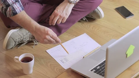 Close-up of an architect sitting on the floor with a laptop and drawing on paper Stock Footage 86768785