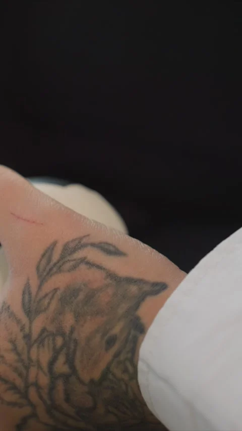 Close up of arm with detailed tattoos resting on white and black soccer balls Stock Footage 344669109