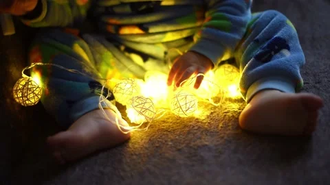Close-up arms of kid boy playing with christmas  garland .Magic vibe of new yea Video stock 220868428