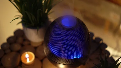 Close up of aroma electric oil diffuser lamp, candles on wooden table in room. Video stock 129295241